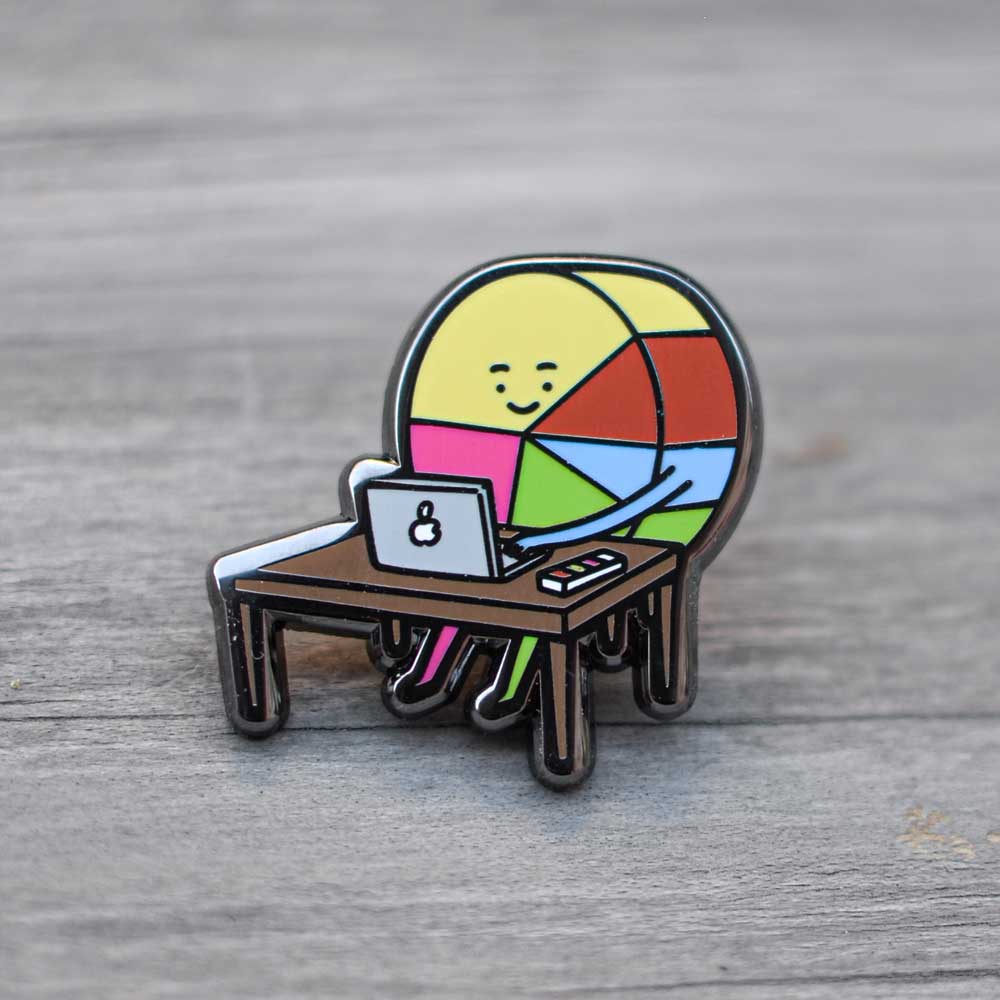 Pin Diseñador Gráfico Ingesman sobre mesa de madera